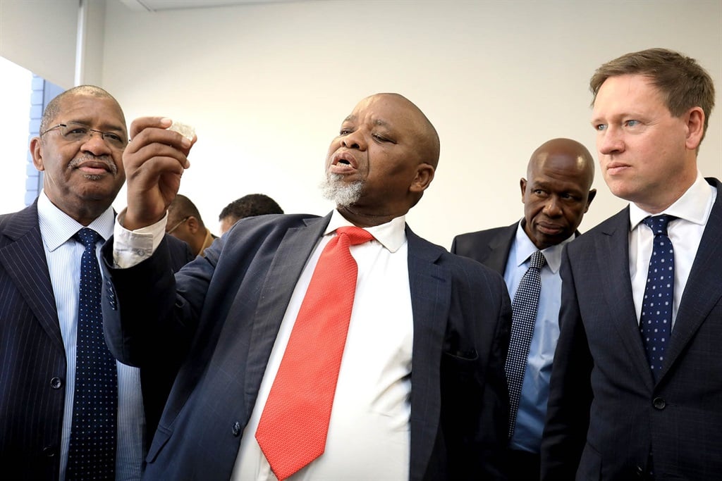 Gwede Mantashe miniszter (középen) a De Beers vezérigazgatójával, Al Cookkal (jobbra) megvizsgál egy gyémántot a csoport új sightholder létesítményének megnyitásakor Johannesburgban 2023 májusában.