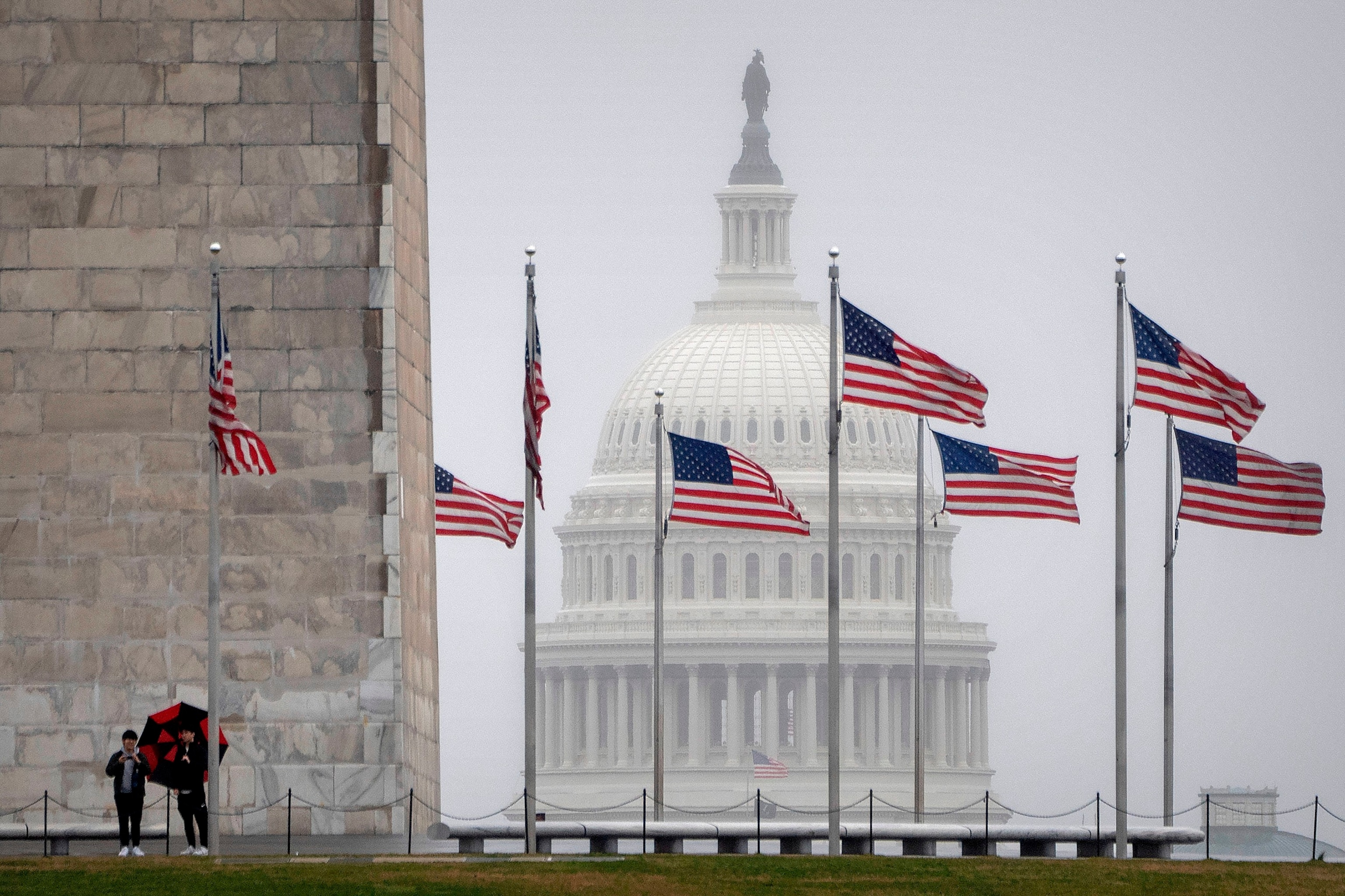 FOTÓ: A látogatók a Washington-emlékmű tövében állnak, ahogy a Capitolium kupolája a távolban látható egy esős reggelen, 2024. március 5-én Washingtonban.