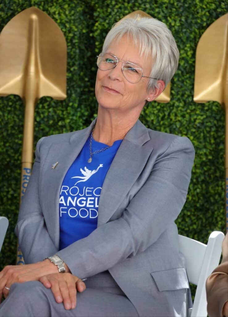 Jamie Lee Curtis, ahogy egy székben ül, pixie frizurát visel, őszülő fehér hajjal