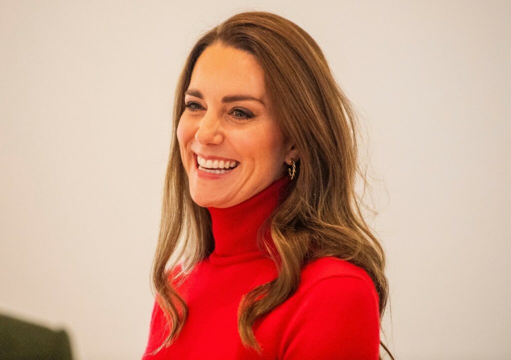 Kate Middleton, portréfotó, vörös ládában, ahogy mosolyog.